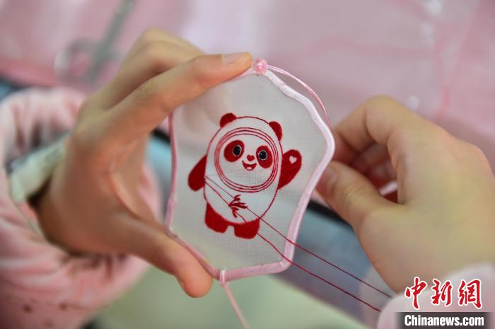 圖為一名小學生正在繡制2022年北京冬奧會吉祥物“冰墩墩”形象?！∮髟屏?攝