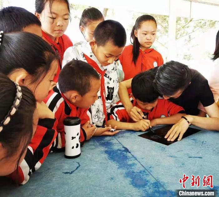 圖為朱增平(右一)教學(xué)生創(chuàng)作鍥金畫。(資料圖) 受訪者供圖