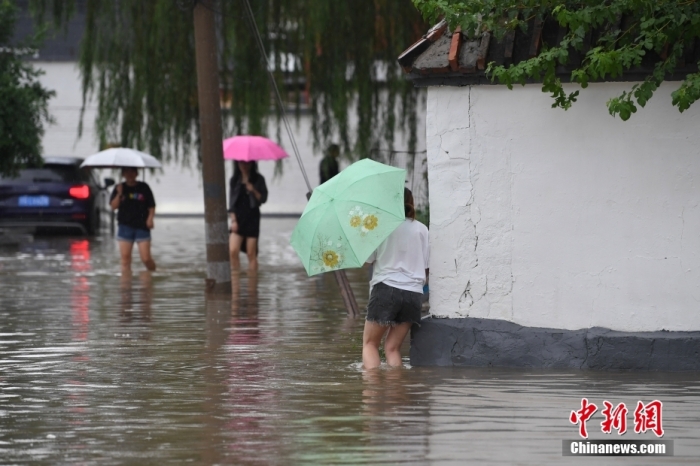 7月31日，市民行走在雨中的北京房山區(qū)瓦窯頭村。北京市氣象臺當(dāng)日10時(shí)發(fā)布分區(qū)域暴雨紅色預(yù)警信號。北京市水文總站發(fā)布洪水紅色預(yù)警，預(yù)計(jì)當(dāng)日12時(shí)至14時(shí)，房山區(qū)大石河流域?qū)⒊霈F(xiàn)紅色預(yù)警標(biāo)準(zhǔn)洪水。<a target='_blank' href='/'><p  align=