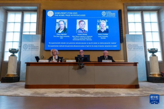 10月3日，在瑞典斯德哥爾摩舉行的2023年諾貝爾物理學(xué)獎公布現(xiàn)場，屏幕上顯示獎項得主皮埃爾·阿戈斯蒂尼（左）、費(fèi)倫茨·克勞斯（中）和安妮·呂利耶的照片。新華社發(fā)（魏學(xué)超攝）