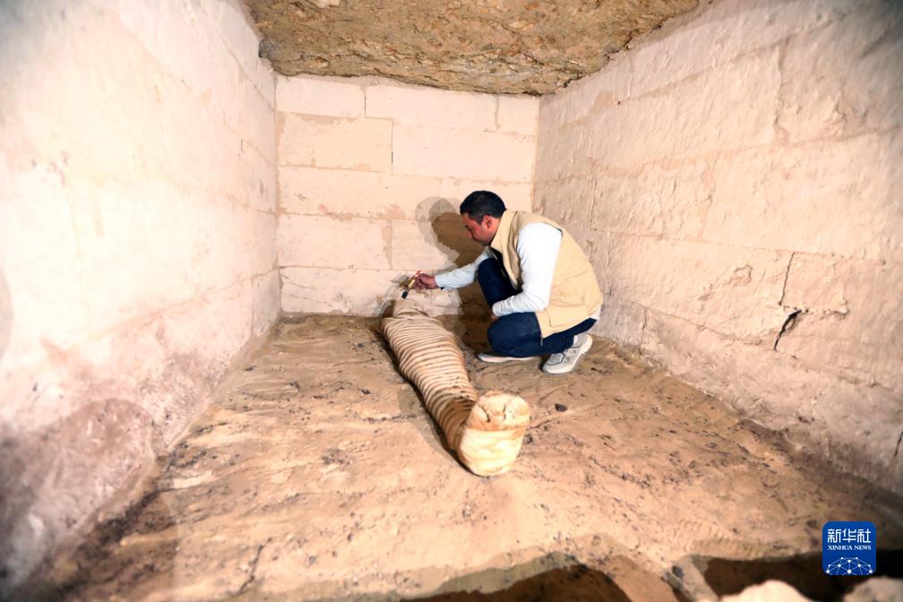 10月15日，在埃及明亞省考古現(xiàn)場(chǎng)，考古人員清理一座石鑿墓中的木乃伊。新華社發(fā)（艾哈邁德·戈馬攝）