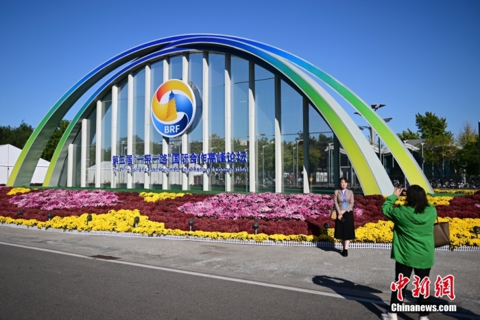 10月15日，北京，工作人員在國(guó)家會(huì)議中心外的第三屆“一帶一路”國(guó)際合作高峰論壇景觀布置前拍照留念。當(dāng)日，位于國(guó)家會(huì)議中心的第三屆“一帶一路”國(guó)際合作高峰論壇新聞中心啟動(dòng)試運(yùn)行。據(jù)悉，第三屆“一帶一路”國(guó)際合作高峰論壇將于10月17日至18日在北京舉行。<a target='_blank' href='/'><p  align=