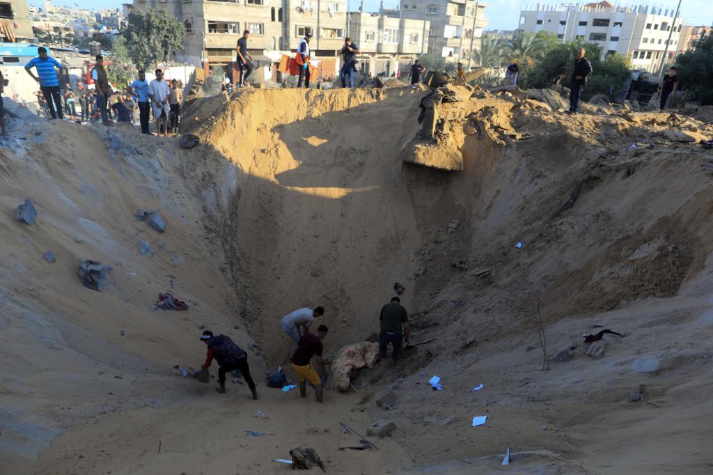 10月16日，在加沙地帶南部城市汗尤尼斯，人們在遭以色列襲擊后的建筑廢墟中救援傷者。 新華社發(fā)（亞西爾·庫迪 攝）