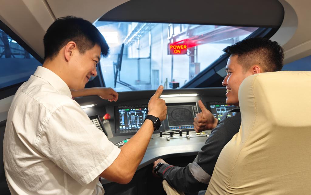 8月25日，在印度尼西亞萬隆的雅萬高鐵德卡魯爾動車所內(nèi)，中國師傅穆振（左）在向印尼火車司機塞蒂亞萬講解動車組出庫前的上電作業(yè)。