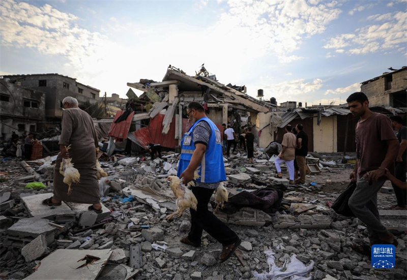 10月27日，在加沙地帶南部城市汗尤尼斯，人們經(jīng)過(guò)以軍襲擊后的房屋廢墟。