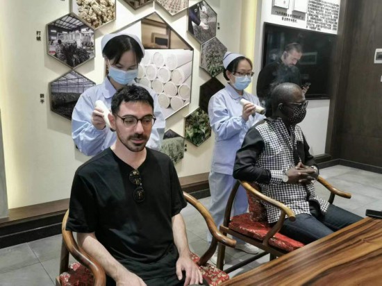 2023“一帶一路”媒體合作論壇聯(lián)合采訪團團員在九牛草展示館體驗艾灸。（本報記者 黃超攝）