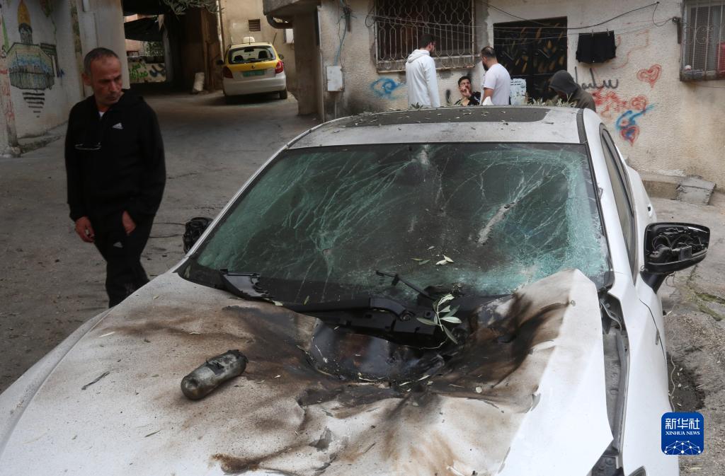 12月17日，在約旦河西岸城市圖勒凱爾姆附近的一處難民營，人們查看在沖突中損毀的車輛。新華社發(fā)（尼達爾·艾仕塔耶攝）