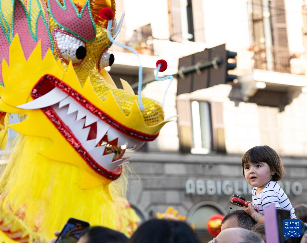 2月18日，在意大利羅馬，一名小朋友在彩妝巡游上觀看舞龍。新華社記者 李京 攝