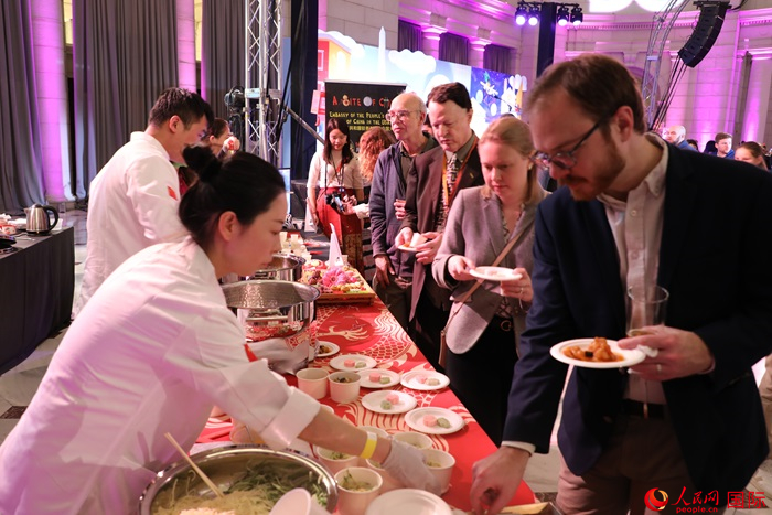 當(dāng)?shù)貢r(shí)間3月7日晚，華盛頓聯(lián)合車(chē)站廣場(chǎng)舉行駐美使團(tuán)“使館主廚挑戰(zhàn)賽”。圖為當(dāng)?shù)孛癖娫谥袊?guó)展臺(tái)前體驗(yàn)中國(guó)美食。人民網(wǎng)記者 李志偉攝