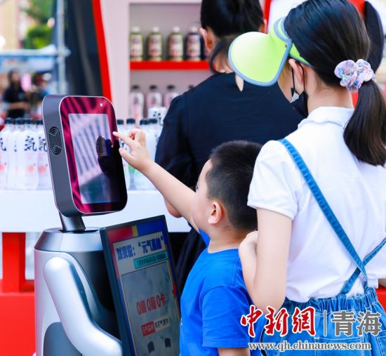 圖為一名小朋友正在和機(jī)器人“志愿者”進(jìn)行互動(dòng)。 沐聞 攝