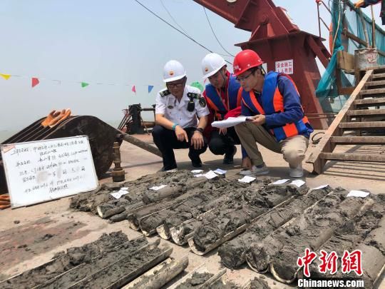 圖為勘察設(shè)計(jì)人員與海事局工作人員查看巖芯情況。　魏震 攝