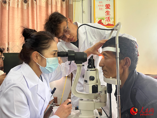 王紅英（左）和團(tuán)隊(duì)成員為達(dá)熱村村民檢查眼睛。人民網(wǎng)記者 杜燕飛攝