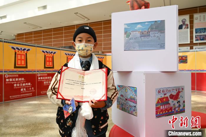 圖為一名獲獎學生與自己的繪畫作品合影?！≮w朗 攝