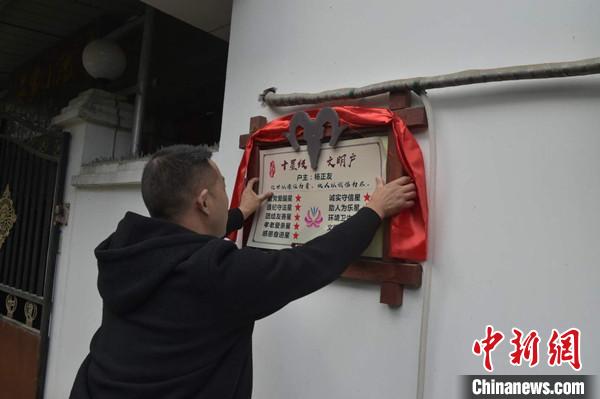 桂溪鎮(zhèn)渭溝村政府工作人員為“十星級文明戶”掛上牌匾。　楊勇 攝