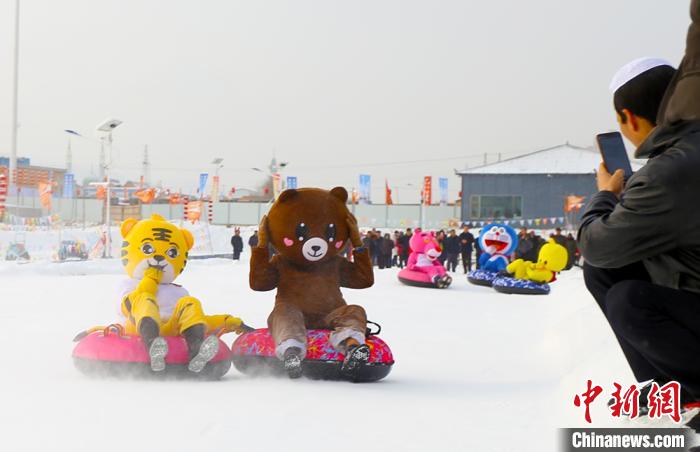 圖為臨夏市南龍鎮(zhèn)馬家莊村舉辦的鄉(xiāng)村文化旅游節(jié)上，游客穿著卡通服裝在體驗(yàn)雪上飛碟項(xiàng)目。近年來，臨夏州形成了“春賞花、夏避暑、秋摘果、冬玩雪”的全季節(jié)旅游產(chǎn)品體系。(資料圖) 高展 攝