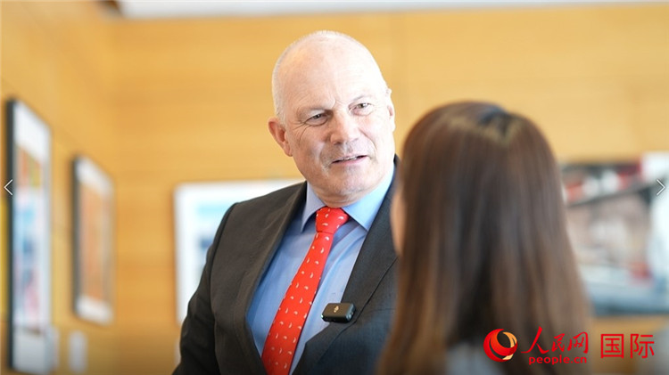 瑞士駐華大使白瑞誼介紹使館內(nèi)陳列的照片。人民網(wǎng) 彭昱凱攝