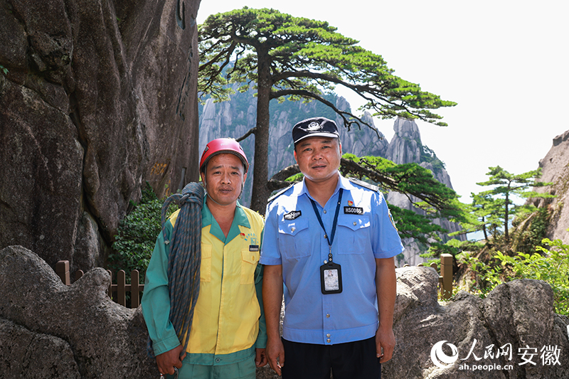 全國道德模范李培生（左）和胡曉春在迎客松前合影。人民網記者 張俊攝