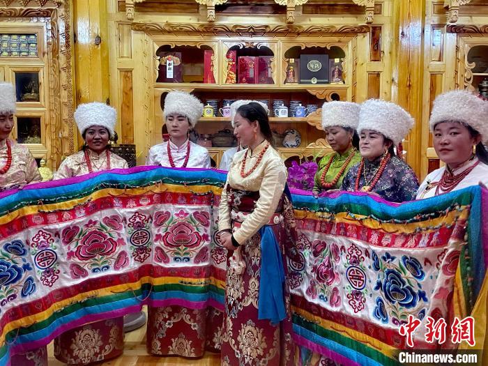 圖為女性展示村民自發(fā)繡制的“百米五彩哈達”?！±钣穹?攝