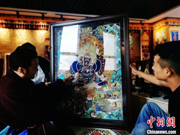 圖為久美尖措(左)與徒弟們展示唐卡作品?！?zhí)砀?攝