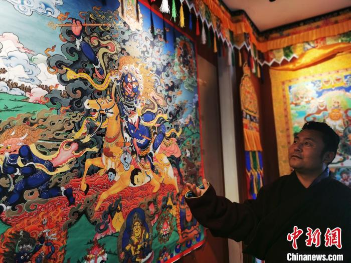 圖為久美尖措展示唐卡作品?！?zhí)砀?攝