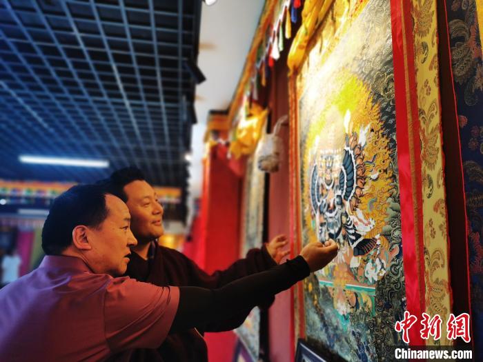 圖為久美尖措展示唐卡作品?！?zhí)砀?攝