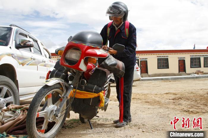 圖為白瑪準(zhǔn)備騎摩托車巡湖?！≮w朗 攝