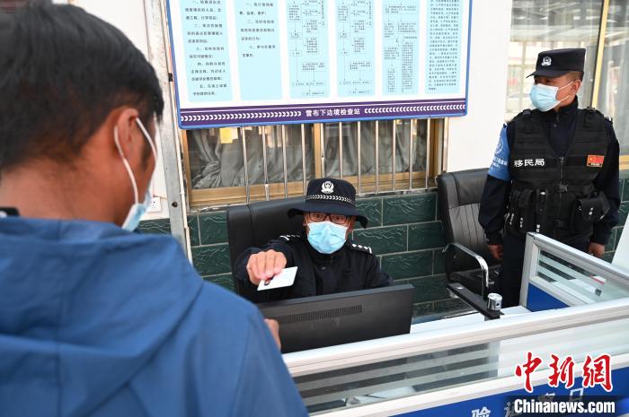 圖為移民管理警察登記完身份信息后將證件歸還給行人?！≮w朗 攝