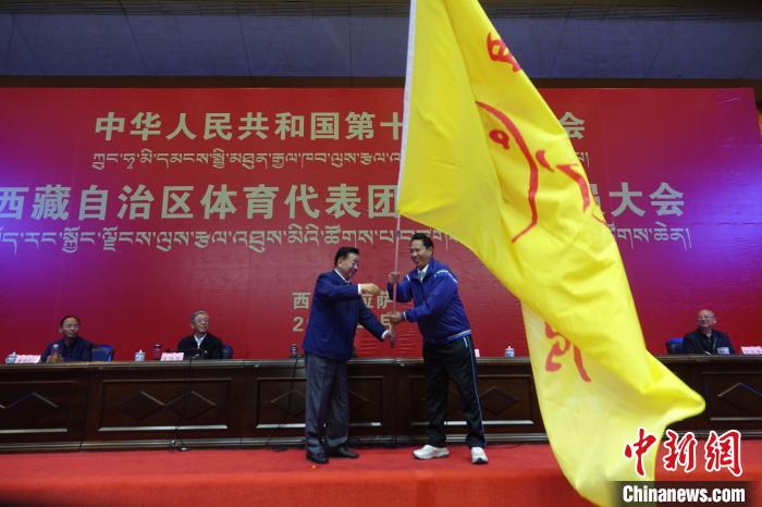 西藏自治區(qū)副主席甲熱·洛桑丹增授代表團(tuán)團(tuán)旗，西藏自治區(qū)體育局局長尼瑪次仁接旗。　冉文娟 攝