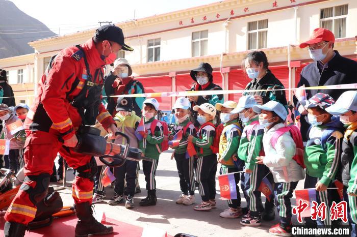 圖為消防指戰(zhàn)員為學(xué)生講解、演示先進救援裝備?！≮w琳 攝