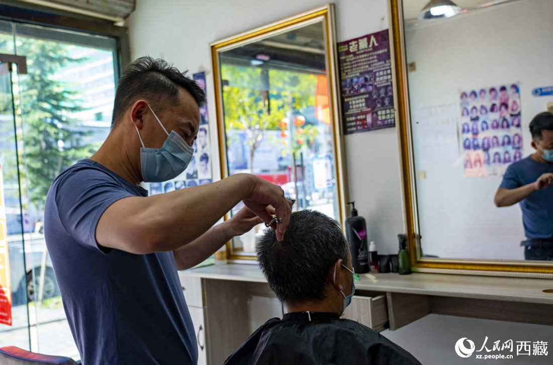 理發(fā)店老板為顧客理發(fā)。次仁羅布 攝