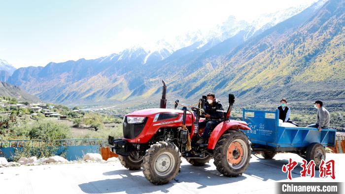 圖為工作人員將把加工完成的糌粑運(yùn)送至村民手中?！〖卫杩h融媒體中心供圖