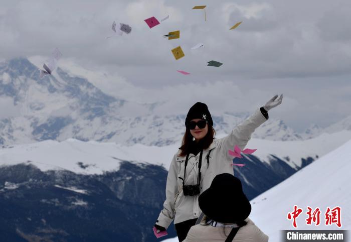 圖為5月14日，游客在西藏林芝色季拉山觀景臺(tái)拋灑“隆達(dá)”(風(fēng)馬旗，藏族民眾的一種祈福方式)?！±盍?攝