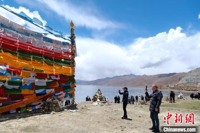 進藏參訪嘉賓在羊湖畔拍攝經(jīng)幡。　江飛波 攝