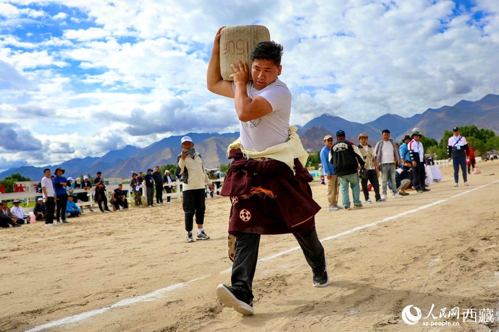 來(lái)自拉薩市當(dāng)雄縣的牧民選手將一塊150斤重的石頭扛在肩上飛奔。