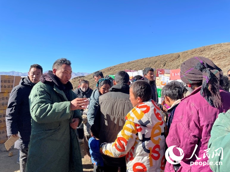 定日縣公安局干警頓珠次仁（左二）正在協(xié)助分發(fā)物資。人民網(wǎng)記者 郝潔攝